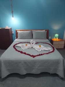 a bed with two towels in a heart shape at Pousada Melodia do Mar in Cabo Frio