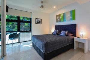 a bedroom with a bed and a desk and windows at Edge Waterfront Apartments in Hamilton Island