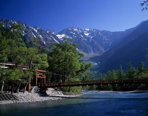 un ponte su un fiume con montagne sullo sfondo di Yakushidaira Akanejyuku a Matsumoto