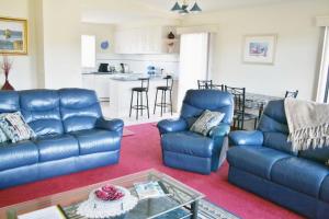 a living room with two blue couches and a kitchen at 526 Arthur Kaine Dr Merimbula in Merimbula