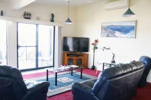 a living room with two leather couches and a tv at 526 Arthur Kaine Dr Merimbula in Merimbula