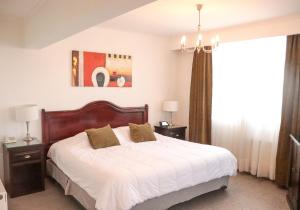 Un dormitorio con una cama con sábanas blancas y una lámpara de araña. en Hotel Terrano Concepción en Concepción