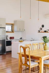 a white kitchen with a wooden table and chairs at Modern Waterfront House at Susans Bay, Primrose in Primrose Sands