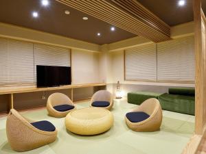 sala de estar con sillas y TV de pantalla plana en Ryokan Okayama en Akakura