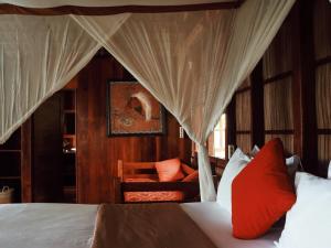 1 dormitorio con 1 cama con cortinas y silla en Raja Ampat Eco Lodge, en Tapokreng