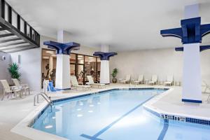 uma piscina no átrio do hotel com cadeiras e mesas em Sheraton Syracuse University Hotel and Conference Center em Syracuse