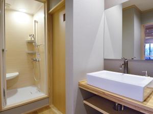 a bathroom with a white sink and a shower at Ryokan Okayama in Akakura