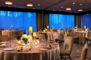 una sala de banquetes con mesas y sillas y manteles blancos. en Sheraton La Jolla, en San Diego