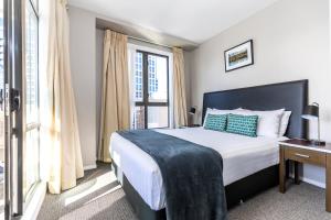 um quarto com uma cama e uma grande janela em Quest on Queen Serviced Apartments em Auckland