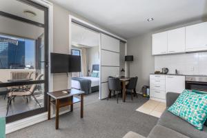 a living room with a couch and a table and a kitchen at Quest on Queen Serviced Apartments in Auckland