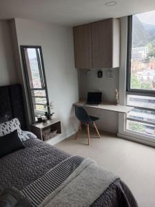 1 dormitorio con 1 cama, escritorio y ventanas en Loft en centro de Bogotá, hermosa vista y confort, en Bogotá