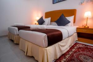 2 aparte bedden in een hotelkamer met een rood tapijt bij العاصمة للشقق الفندقية - Capital Hotel Apartments in Muscat