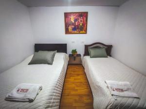 2 camas en una habitación con sábanas blancas y almohadas verdes en Hotel El Molino, en Facatativá