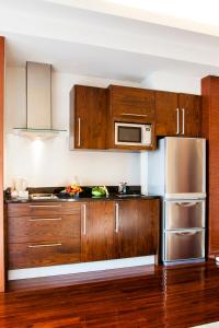 a kitchen with wooden cabinets and a stainless steel refrigerator at Column Bangkok Hotel in Bangkok