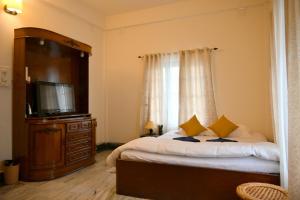 um quarto com uma cama e uma televisão de ecrã plano em Bhaskar Homestay - The Bungalow em Dibrugarh