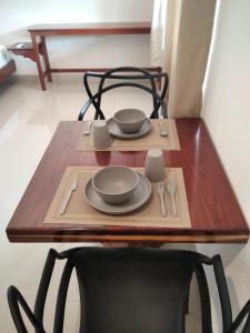 una mesa de madera con platos y utensilios. en Apartamento en Bacalar