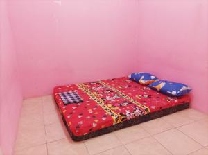 a bed in a room with a pink wall at SLAMET HOMESTAY TASIKMALAYA in Tasikmalaya