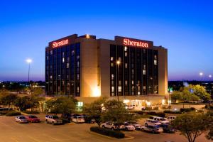 a building with cars parked in a parking lot at Sheraton West Des Moines in West Des Moines