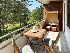 a small balcony with a wooden table and chairs at Ferienwohnung Möwenweg 9 Whg 28 in Wittdün