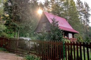 une maison avec un toit rouge derrière une clôture dans l'établissement In The Woods - Chata w lesie na wyłączność, à Supraśl