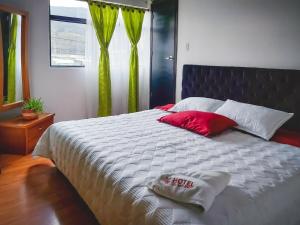 Un dormitorio con una cama grande con almohadas rojas. en Hotel El Molino, en Facatativá