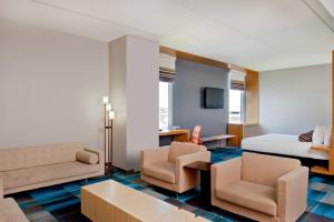 a hotel room with a bed and a couch and chairs at Aloft Bolingbrook in Bolingbrook