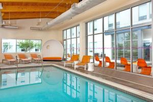 an indoor pool with orange chairs and a poolside at Aloft Bolingbrook in Bolingbrook