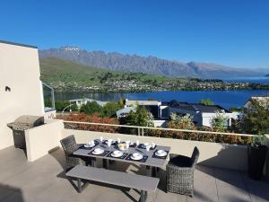 a table and chairs on a balcony with a view of the water at Luxury Home with Beautiful Lake & Mountain Views in Queenstown
