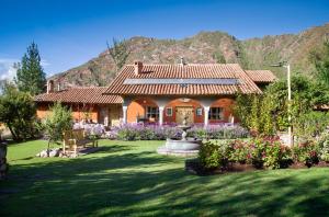 a house with a fountain in a yard with mountains at VILLA APU CHICON (Apu Wasi & Inti Wasi) in Urubamba