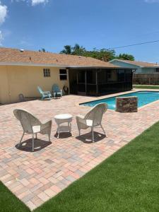 a patio with two chairs and a table and a pool at Beautiful house in lake worth,close to the beach! in Lake Worth