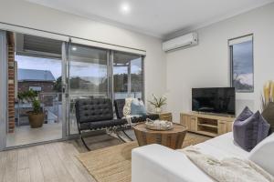 uma sala de estar com um sofá e uma televisão em Modernista Getaway Your Airport Retreat em Perth