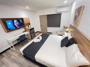 una camera con un grande letto bianco e una TV a schermo piatto di Katherine Motel a Katherine