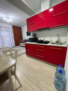 博斯特里的住宿－Танхаус в Байтур резорте и Спа，一间带红色橱柜和桌子的厨房以及一间用餐室