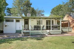 Cette petite maison blanche dispose d'une terrasse couverte et d'un barbecue. dans l'établissement Toorak Place, à Bright