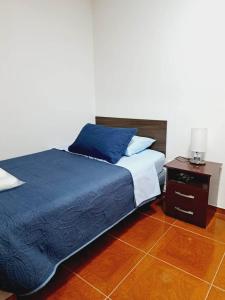 1 dormitorio con cama azul y mesita de noche en Residencial SOL NACIENTE en Pozo Almonte