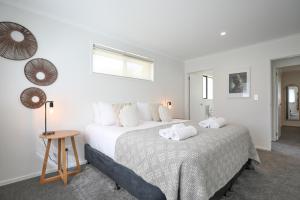 a white bedroom with two beds and a table at Redwoods Adventure Base in Rotorua