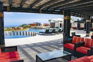 un patio con tavolo, sedie e piscina. di Breathtaking Ocean Views and Access Best Resorts! a Cabo San Lucas