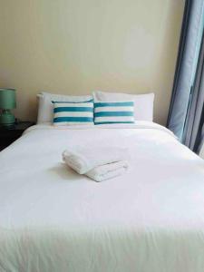 a white bed with blue and white pillows at One Uptown Residence Prime Loc BGC,Uptown Linked 1BR,Washer,200mbps in Manila