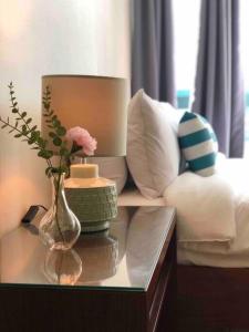 a table with a vase with flowers and a lamp at One Uptown Residence Prime Loc BGC,Uptown Linked 1BR,Washer,200mbps in Manila