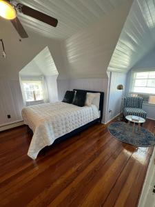 a bedroom with a bed and a chair and wooden floors at Inkwell Beach Cottage in Oak Bluffs