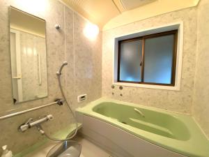 a bathroom with a green tub and a window at 跳びしまBASE in Mitarai
