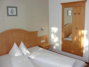 Schlafzimmer mit einem weißen Bett und einem Spiegel in der Unterkunft Gästehaus Loithaler in Fügen