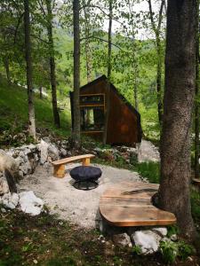 una cabaña en el bosque con un banco y un árbol en Mountain lodge Forte Emilia, en Kobarid