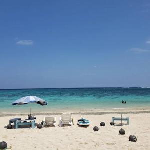 a beach with chairs and an umbrella and the ocean at 宮古島ゲストハウス　マウイ in Arazato