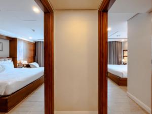 a bedroom with two beds and a mirror at Paris Deli Danang Beach Hotel in Danang