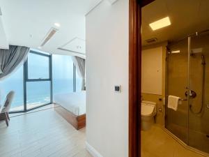 a bathroom with a shower and a toilet and a bed at Paris Deli Danang Beach Hotel in Danang