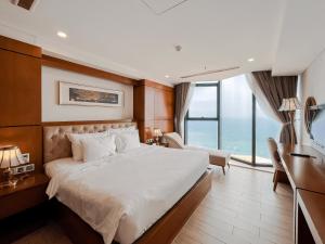 a bedroom with a large bed and a large window at Paris Deli Danang Beach Hotel in Danang