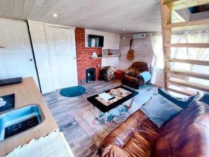 a living room with a leather couch and a table at Charming Sauna Cottage in a Horse Ranch in Lieplaukė