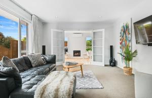 uma sala de estar com um sofá de couro preto em Family-Friendly, Airport 6 mins, Spacious with Garden em Christchurch