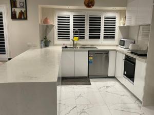 a kitchen with white counter tops and appliances at Refurbished Family Home in Glen Waverley